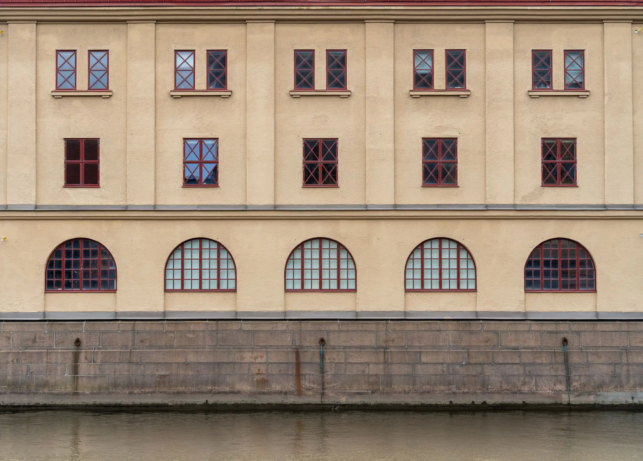 Ljus stenfasad med valvfönster speglad i kanalen